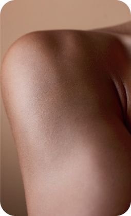 Immagine di una superficie cutanea liscia e illuminata, tonalità di pelle naturale, dettaglio di spalla e contorni morbidi.
