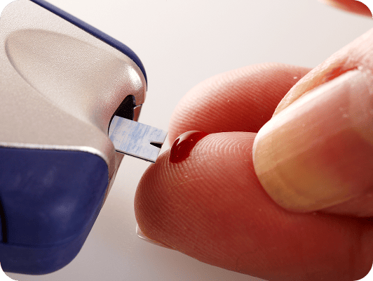 Taglio di un campione di sangue con una microletto, evidenziando la punta e una goccia rossa sul dito