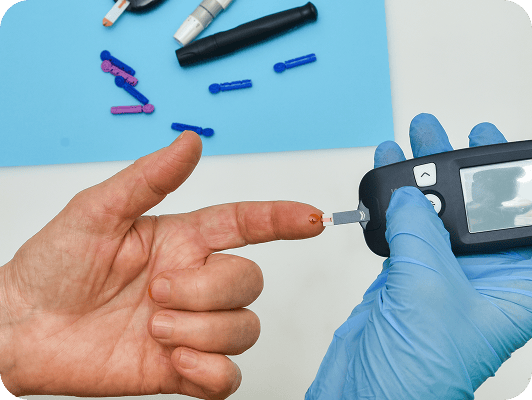 Analista usa glucometro per misurare zucchero sul sangue dal dito, con guanti blu e piastra con puntali colorati sullo sfondo.