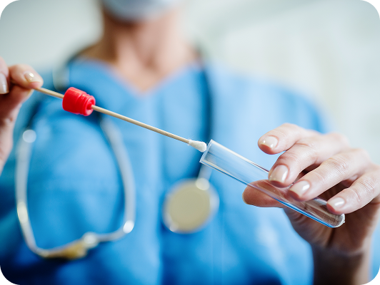 Tecnico medico in camice azzurro con stetoscopio, intento disinfettare o preparare una provetta con cottone per campione biologico.