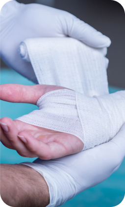 Polso avvolto in bendaggio bianco, con guanti chirurgici, pronto per medicazione.