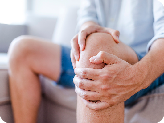 Persona che è seduta, tiene un ginocchio dolorante con entrambe le mani