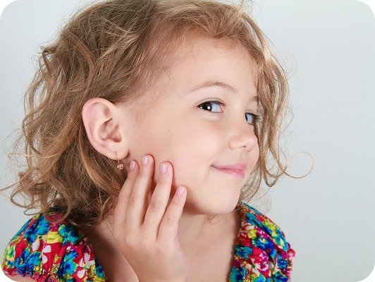 Ragazza giovane con capelli ricci, sguardo sornione e mano sul viso, abito colorato vivace in primo piano.