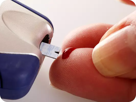 Taglio di un campione di sangue con una microletto, evidenziando la punta e una goccia rossa sul dito