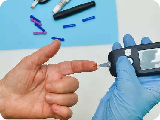 Analista usa glucometro per misurare zucchero sul sangue dal dito, con guanti blu e piastra con puntali colorati sullo sfondo.