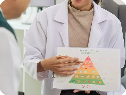 Professionista in camice bianca presenta una piramide alimentare su una plancia informativa, evidenziando una guida nutrizionale.