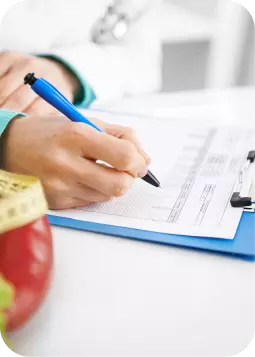 Mano che scrive su modulo fiscale su lavagna blu; vicino cesto di frutta e documenti, atmosfera da ufficio.