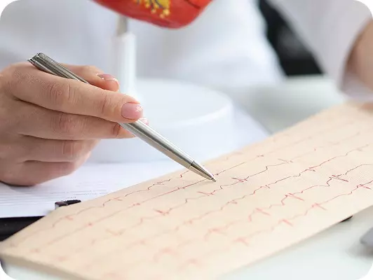 Mano che con penna stilografica controlla i risultati di un elettrocardiogramma