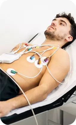 Uomo seduto su lettino con monitoraggio medico: elettrodi e sensori attaccati al torace