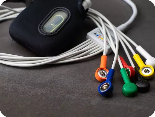 Elettrodi di elettrocardiogramma (ECG) collegati a un motivatore bianco, con custodia nera sullo sfondo e cavi colorati posizionati in primo piano.