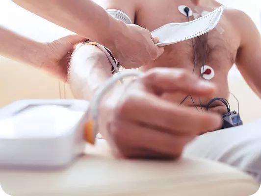 Mano di un operatore sanitario che applica sul braccio di un uomo un misuratore di pressione durante una visita medica