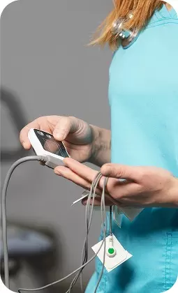 Donna in camicia azzurra tiene cavi e un dispositivo elettronico in mano