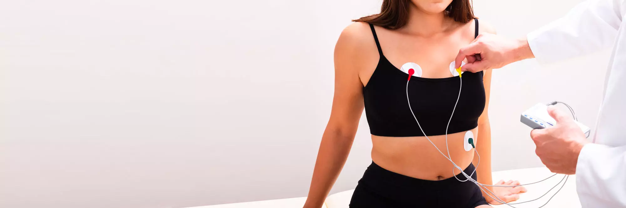 Donna in top nero con elettrodi adesivi sul petto durante monitoraggio medico