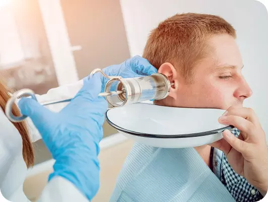 Uomo seduto riceve trattamento di lavaggio auricolare in ambiente clinico