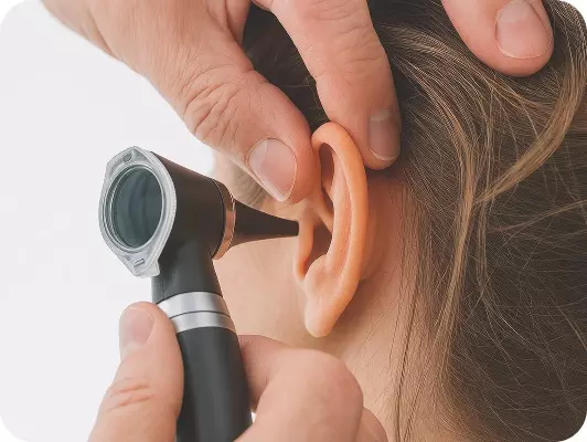 Medico esegue un controllo all'orecchio sinistro, primo piano su orecchio e dispositivo.