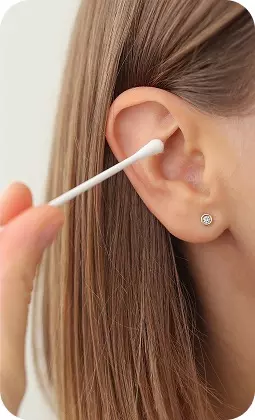 Pulizia dell'orecchio con cotton fioc, dettaglio orecchio femminile con orecchino, primo piano.