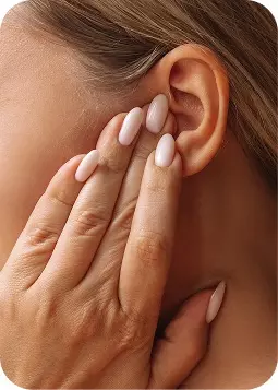 Primo piano di mano femminile con unghie lunghe e rosate sull’orecchio.