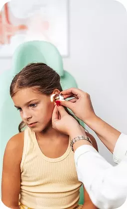 Bambina in clinica mentre un medico inserisce un piccolo cerotto all'orecchio sinistro.