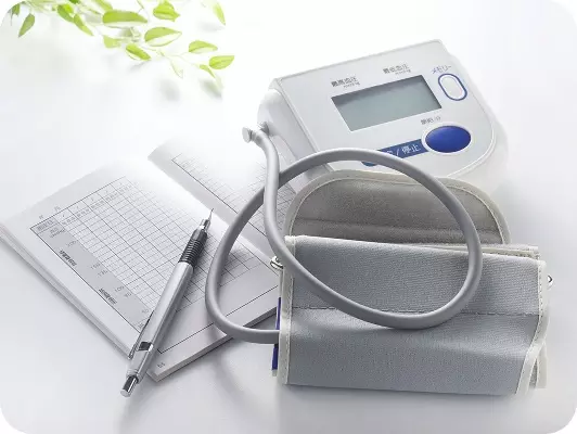 Manometro e sfigmomanometro digitale su sfondo bianco, con grafico e penna su foglio: ambiente medico pulito e professionale per misurazione pressione.