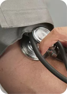 Medico che ascolta il paziente con stetoscopio sul braccio: scena clinica professionale, focus su camice e stetoscopio.