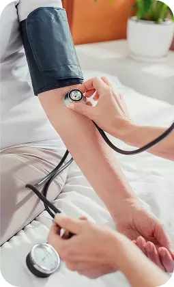 Persona che sta misurando la pressione arteriosa sul braccio sinistro con sfigmomanometro, in ambiente clinico