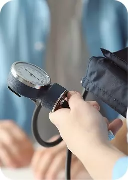 Braccio di una persona che tiene un sfigmomanometro in primo piano; la manichetta avvolta sul braccio indica una misurazione della pressione sanguigna.