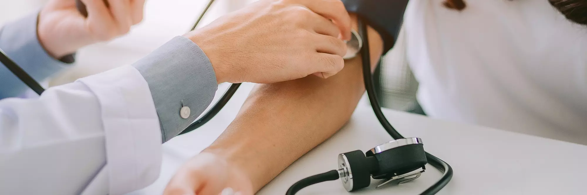 Medico che misura la pressione sanguigna di un paziente usando lo sfigmomanometro sul braccio.