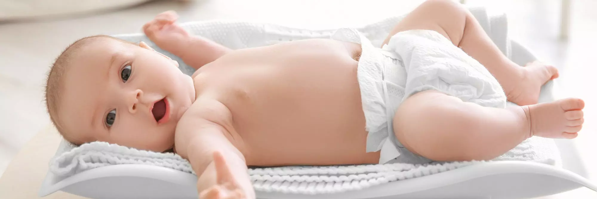 Neonato disteso su una coperta, occhi aperti e espressione curiosa