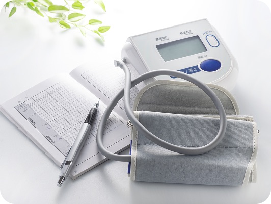 Manometro e sfigmomanometro digitale su sfondo bianco, con grafico e penna su foglio: ambiente medico pulito e professionale per misurazione pressione.