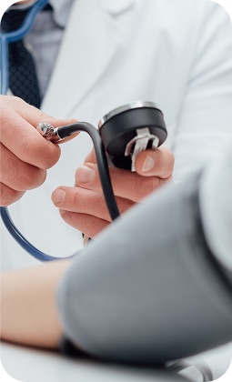 Medico con stetoscopio pronto a misurare la pressione del paziente in un ambiente clinico, focus sulle mani e strumenti.