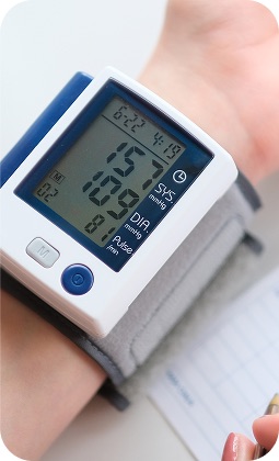 Bracciale elettronico con lettore di pressione sanguigna, schermo digitale e pulsanti, monitoraggio salute su polso.