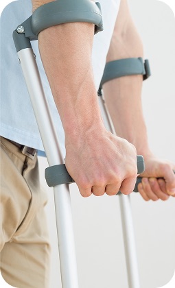 Uomo con stampelle appoggiate sulle braccia, mani ferme, in primo piano, supporto per deambulazione.