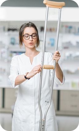 Assistente sanitaria con camice bianco mostra una stampella in farmacia